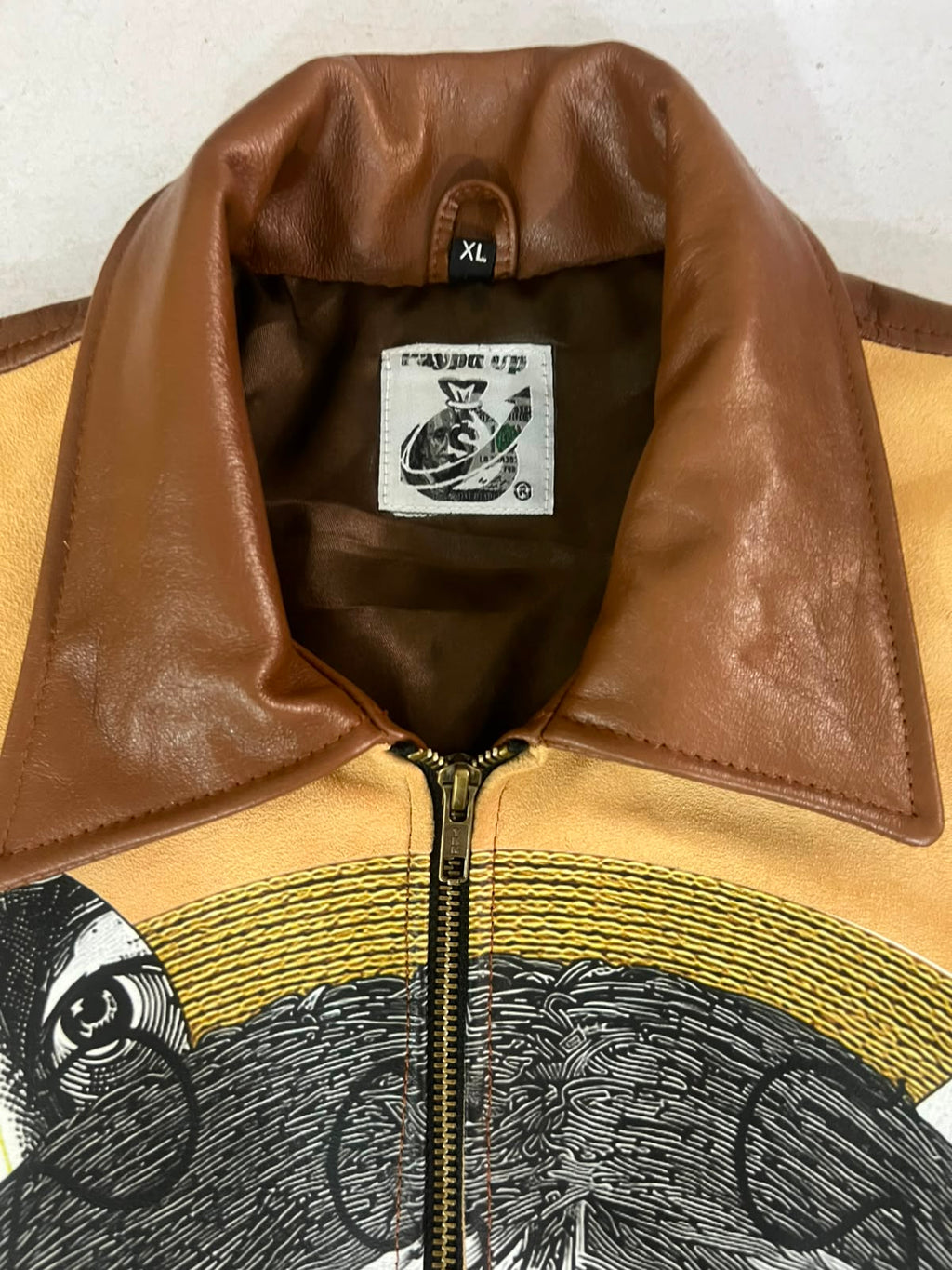 Front view of She Only Loves The Payp Leather Zip Shortsleeve Shirt showing embroidered puzzle collage design