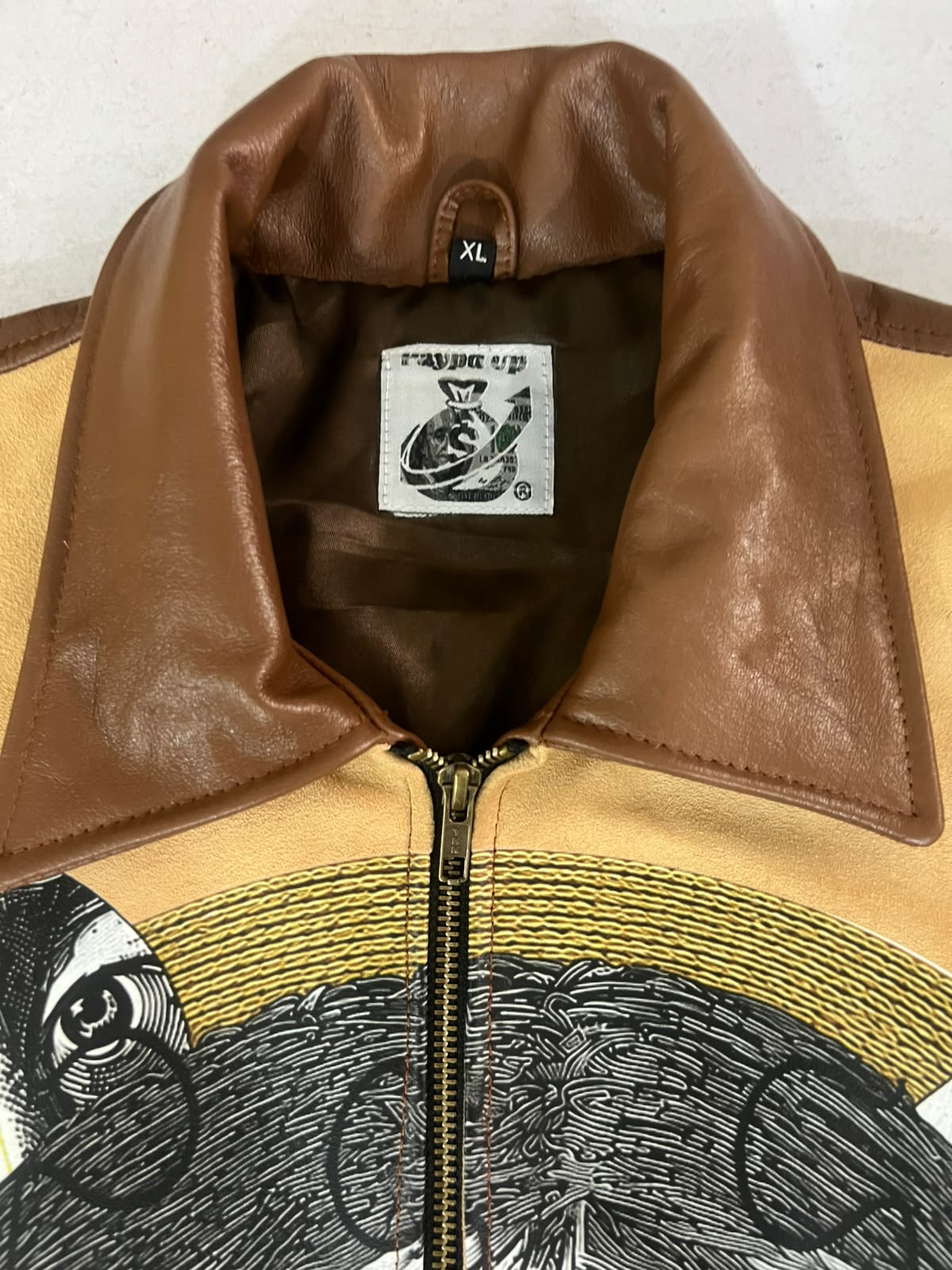 Front view of She Only Loves The Payp Leather Zip Shortsleeve Shirt showing embroidered puzzle collage design